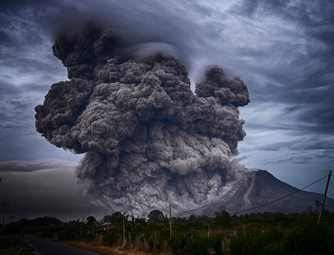 An enormous volcanic ash column erupting into a darkened sky — the Permian Great Dying.